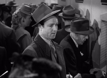 Movie still from “Out of the Past” (1947), directed by Jacques Tourneur – Black and white photograph of a man in a crowd of people; Medium shot, High angle