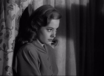 Movie still from “Out of the Past” (1947), directed by Jacques Tourneur – A young woman standing in front of a window; Close Up shot, High angle