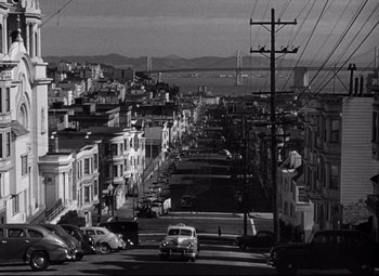 Movie still from “Out of the Past” (1947), directed by Jacques Tourneur – A black and white photo of a city street; Extreme Wide shot, High angle