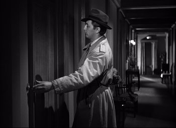 Movie still from “Out of the Past” (1947), directed by Jacques Tourneur – A black and white photo of a man in a trench coat and hat; Medium shot, High angle