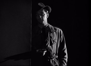 Movie still from “Out of the Past” (1947), directed by Jacques Tourneur – A black and white photo of a man wearing a hat; Medium shot, Low angle
