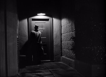 Movie still from “Out of the Past” (1947), directed by Jacques Tourneur – A man in a hat is standing in a dark hallway; Wide shot, Low angle