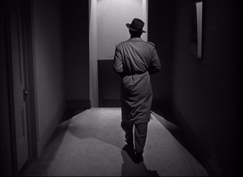 Movie still from “Out of the Past” (1947), directed by Jacques Tourneur – A black and white photo of a man walking down a hall way; Medium shot, High angle
