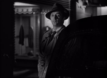Movie still from “Out of the Past” (1947), directed by Jacques Tourneur – A black and white photo of a man wearing a hat; Medium shot, Low angle
