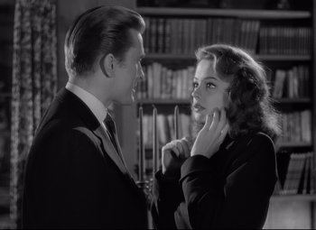 Movie still from “Out of the Past” (1947), directed by Jacques Tourneur – A man and a woman in a room with a bookshelf in the background; Close Up shot, Over the shoulder angle