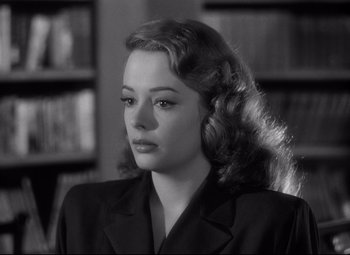 Movie still from “Out of the Past” (1947), directed by Jacques Tourneur – A black - and - white photo of a woman in front of a bookshelf; Close Up shot, Over the shoulder angle