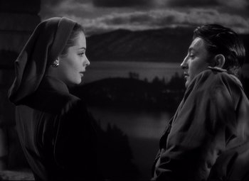 Movie still from “Out of the Past” (1947), directed by Jacques Tourneur – A man and a woman standing next to each other in front of a body of water; Medium shot, Low angle