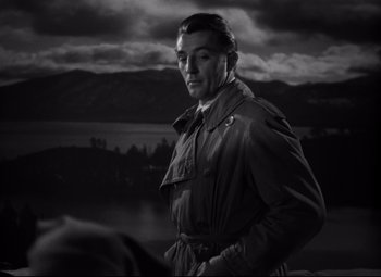 Movie still from “Out of the Past” (1947), directed by Jacques Tourneur – A black and white photo of a man in a trench coat; Close Up shot, Over the shoulder angle