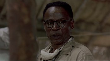 Movie still from “Outbreak” (1995), directed by Wolfgang Petersen – An older man wearing glasses and a tan jacket; Close Up shot, Low angle