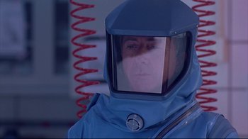 Movie still from “Outbreak” (1995), directed by Wolfgang Petersen – A man in a blue suit and a red hose; Close Up shot, Over the shoulder angle
