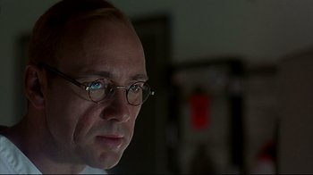 Movie still from “Outbreak” (1995), directed by Wolfgang Petersen – A person wearing glasses and looking to his left; Close Up shot, Low angle