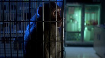 Movie still from “Outbreak” (1995), directed by Wolfgang Petersen – A monkey is sitting in a cage in the dark; Close Up shot, Low angle