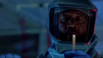 Movie still from “Outbreak” (1995), directed by Wolfgang Petersen – A man in a space suit is holding a stick of food; Close Up shot, Low angle
