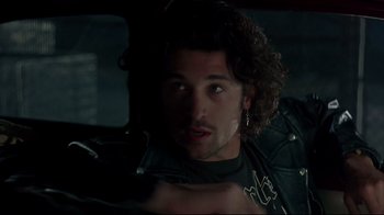 Movie still from “Outbreak” (1995), directed by Wolfgang Petersen – A man in a leather jacket in a car looking at the camera; Close Up shot, Over the shoulder angle