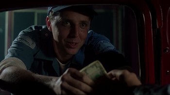 Movie still from “Outbreak” (1995), directed by Wolfgang Petersen – A police officer holding a stack of money in his hand; Close Up shot, Over the shoulder angle