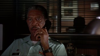 Movie still from “Outbreak” (1995), directed by Wolfgang Petersen – An older man talking on a phone while wearing a uniform; Close Up shot, Low angle