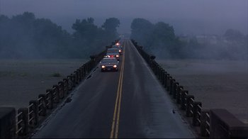 Movie still from “Outbreak” (1995), directed by Wolfgang Petersen – A line of cars driving down a bridge; Extreme Wide shot, High angle