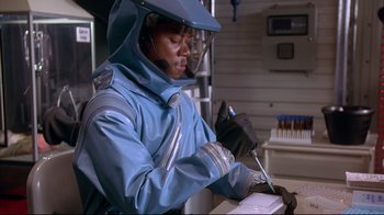 Movie still from “Outbreak” (1995), directed by Wolfgang Petersen – A man in a blue jacket and black gloves; Medium shot, Over the shoulder angle