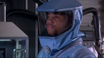 Movie still from “Outbreak” (1995), directed by Wolfgang Petersen – A man wearing a blue suit and a helmet; Close Up shot, Over the shoulder angle