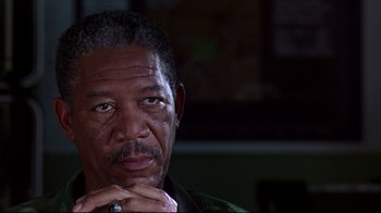 Movie still from “Outbreak” (1995), directed by Wolfgang Petersen – An older man with a black beard and mustache; Close Up shot, Over the shoulder angle