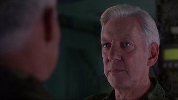 Movie still from “Outbreak” (1995), directed by Wolfgang Petersen – An older man looking at another man in a green room; Close Up shot, Over the shoulder angle