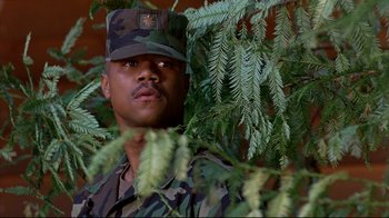 Movie still from “Outbreak” (1995), directed by Wolfgang Petersen – A man in fatigues standing next to a bush; Close Up shot, Low angle