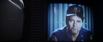 Movie still from “Outland” (1981), directed by Peter Hyams – A man in a blue shirt and a hat; Extreme Close Up shot, Over the shoulder angle