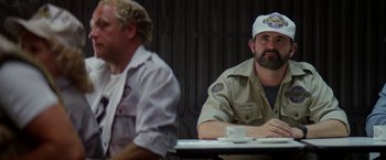 Movie still from “Outland” (1981), directed by Peter Hyams – Two men are sitting at a table and one of them is wearing a hat; Medium shot, Over the shoulder angle
