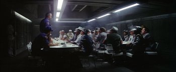 Movie still from “Outland” (1981), directed by Peter Hyams – A group of people sitting around a table; Wide shot, Over the shoulder angle