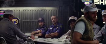 Movie still from “Outland” (1981), directed by Peter Hyams – A group of men sitting at a table with their arms crossed; Medium shot, Over the shoulder angle
