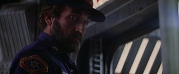 Movie still from “Outland” (1981), directed by Peter Hyams – A man with a beard wearing a hat; Close Up shot, Over the shoulder angle
