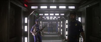 Movie still from “Outland” (1981), directed by Peter Hyams – A group of people standing inside of a building; Wide shot, Over the shoulder angle