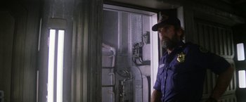 Movie still from “Outland” (1981), directed by Peter Hyams – A man standing in front of an open door; Medium shot, Low angle