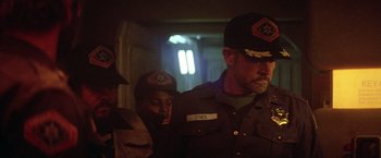 Movie still from “Outland” (1981), directed by Peter Hyams – A group of men standing next to each other in a room; Medium shot, Over the shoulder angle