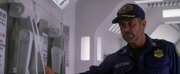 Movie still from “Outland” (1981), directed by Peter Hyams – A man in a police uniform standing next to a wall; Medium shot, Low angle