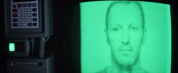 Movie still from “Outland” (1981), directed by Peter Hyams – A man's face is projected on a television screen; Extreme Close Up shot, High angle