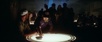 Movie still from “Outland” (1981), directed by Peter Hyams – A man that is playing a game on the table; Medium shot, Over the shoulder angle
