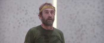 Movie still from “Outland” (1981), directed by Peter Hyams – A man with a beard wearing a yellow headband; Close Up shot, Low angle