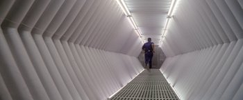 Movie still from “Outland” (1981), directed by Peter Hyams – A man walking down a hallway in a building; Wide shot, High angle