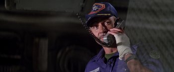 Movie still from “Outland” (1981), directed by Peter Hyams – A man in a blue uniform talking on a phone; Close Up shot, Low angle