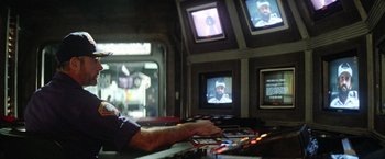 Movie still from “Outland” (1981), directed by Peter Hyams – A man sitting in front of a television; Medium shot, Low angle