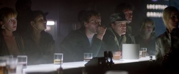 Movie still from “Outland” (1981), directed by Peter Hyams – A man sitting at a table with a drink in front of him; Medium shot, Low angle