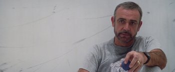 Movie still from “Outland” (1981), directed by Peter Hyams – A person wearing a gray shirt; Close Up shot, Low angle