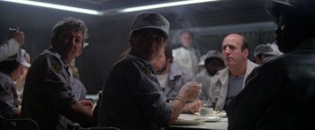 Movie still from “Outland” (1981), directed by Peter Hyams – A group of people sitting around a table; Medium shot, Low angle