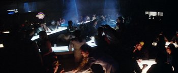 Movie still from “Outland” (1981), directed by Peter Hyams – A group of people sitting in a dark room; Wide shot, High angle