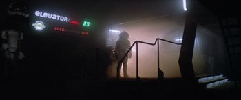 Movie still from “Outland” (1981), directed by Peter Hyams – A person standing in the dark with a fire hydrant in front of them; Wide shot, Low angle