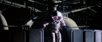 Movie still from “Outland” (1981), directed by Peter Hyams – A man in a spacesuit is standing in the dark; Wide shot, Overhead angle