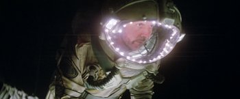 Movie still from “Outland” (1981), directed by Peter Hyams – A man wearing a helmet with lights around it's head; Medium shot, Overhead angle