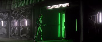 Movie still from “Outland” (1981), directed by Peter Hyams – A man standing in front of a building with green lights; Wide shot, Low angle