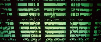Movie still from “Outland” (1981), directed by Peter Hyams – A man walking on a platform in front of a building; Extreme Wide shot, Low angle